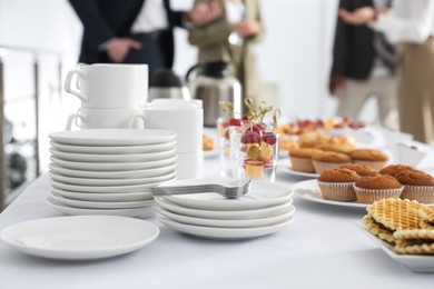 Table with different delicious snacks and dishware indoors. Coffee break