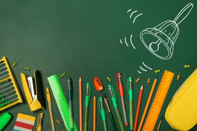 Image of Different stationery and drawn school bell on green chalkboard surface, flat lay