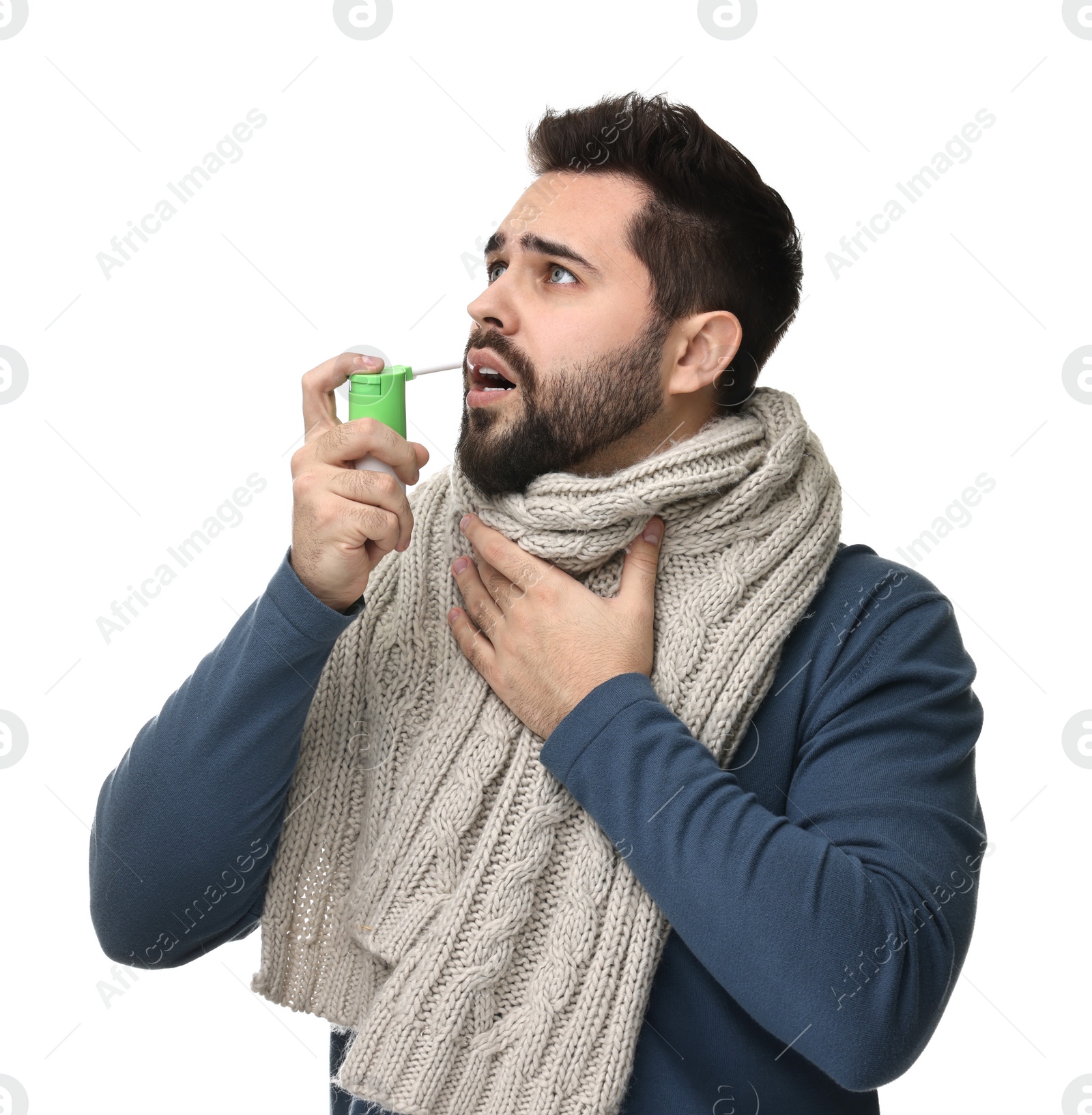 Photo of Young man with scarf using throat spray on white background