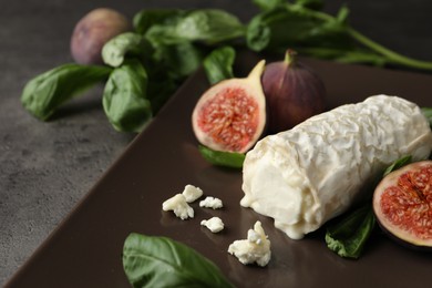 Photo of Delicious goat cheese with figs and basil on grey table, closeup