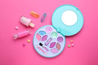 Eye shadow palette and other decorative cosmetics for kids on pink background, flat lay