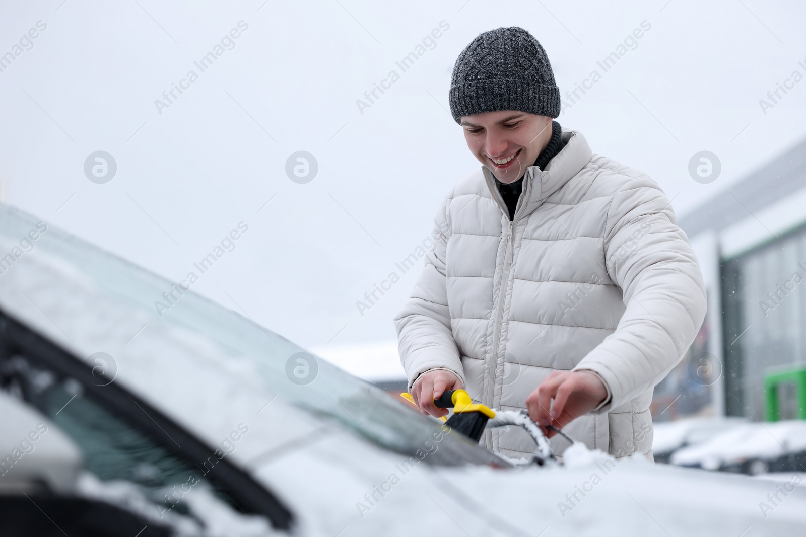 Photo of Man cleaning snow from car windshield outdoors, space for text