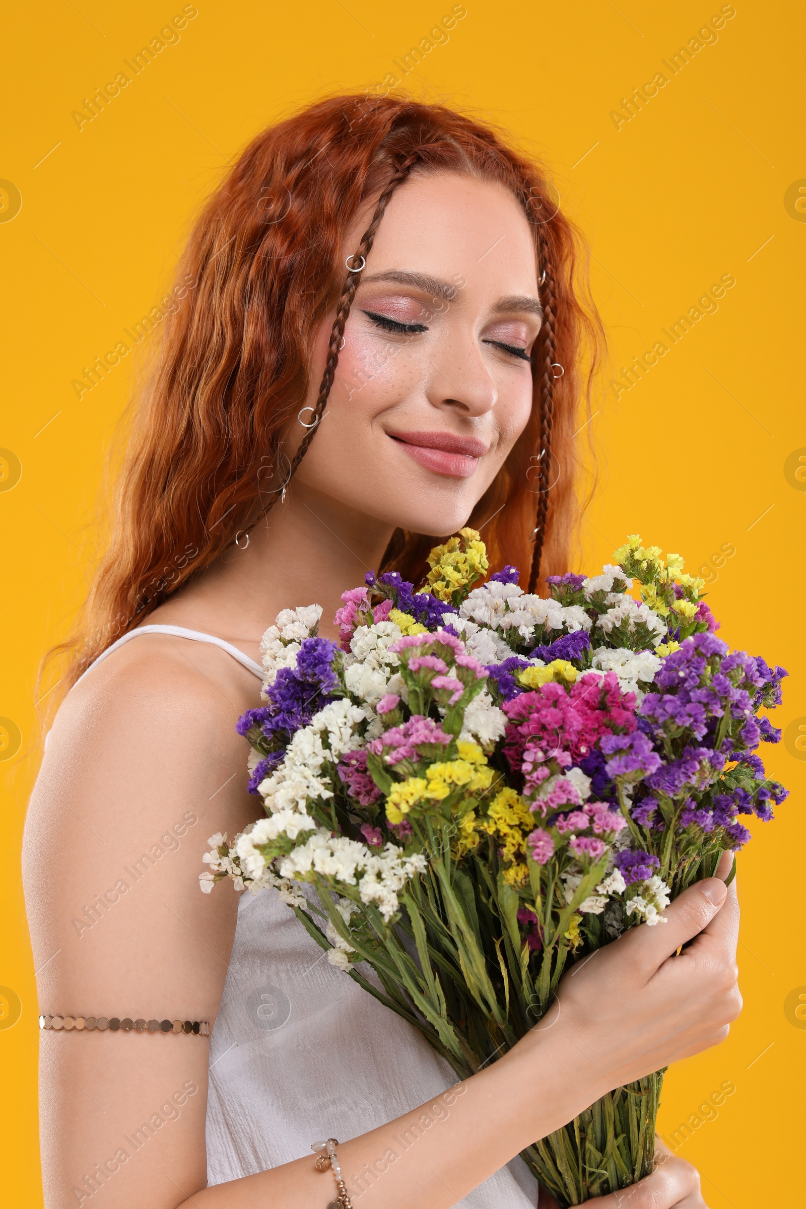 Photo of Beautiful young hippie woman with bouquet of colorful flowers on orange background