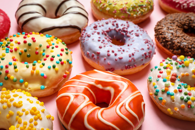 Delicious glazed donuts on pink background, closeup