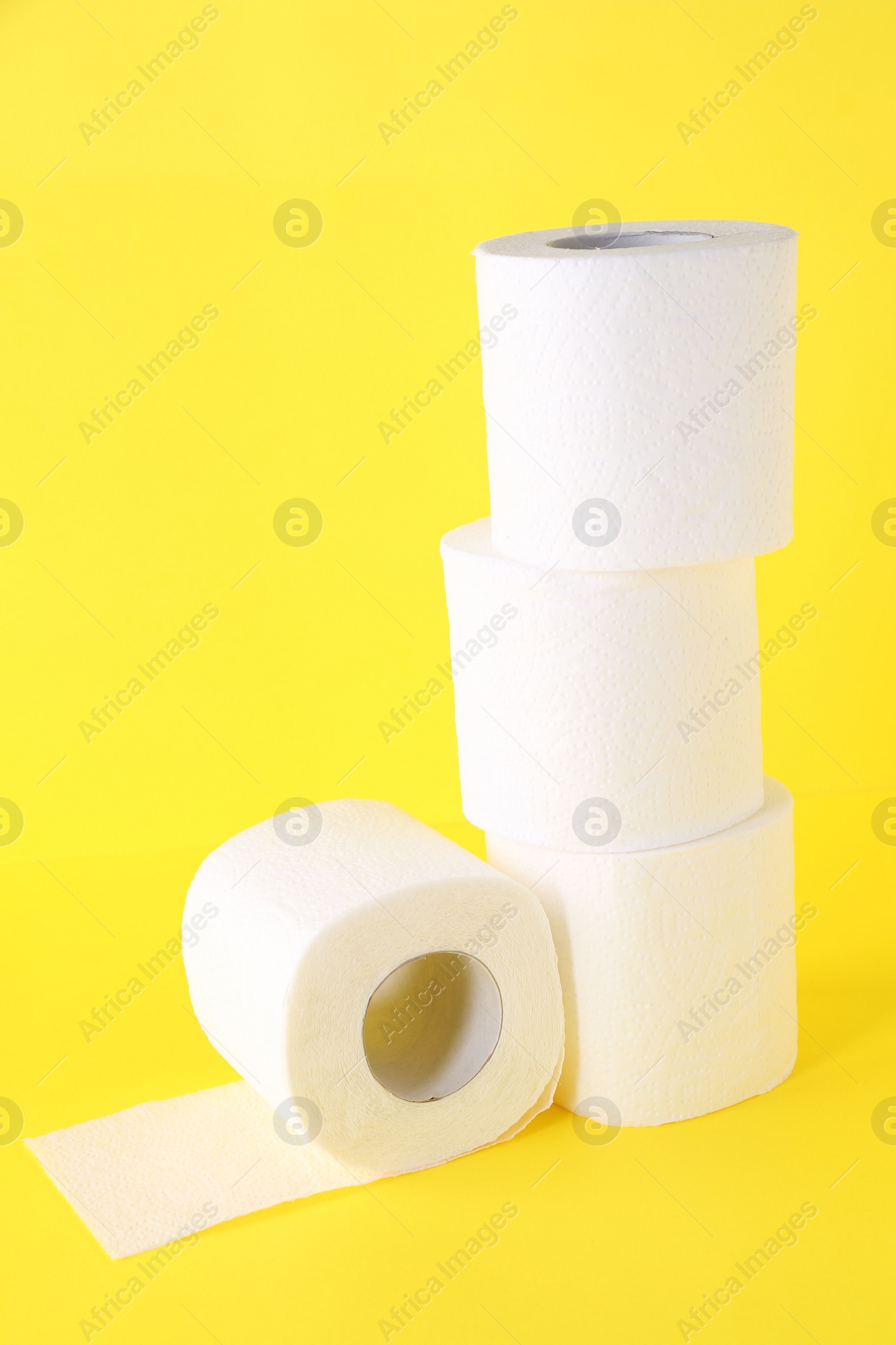 Photo of Many soft toilet paper rolls on yellow background