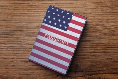 Image of Passport in case with image of American flag on wooden table, top view