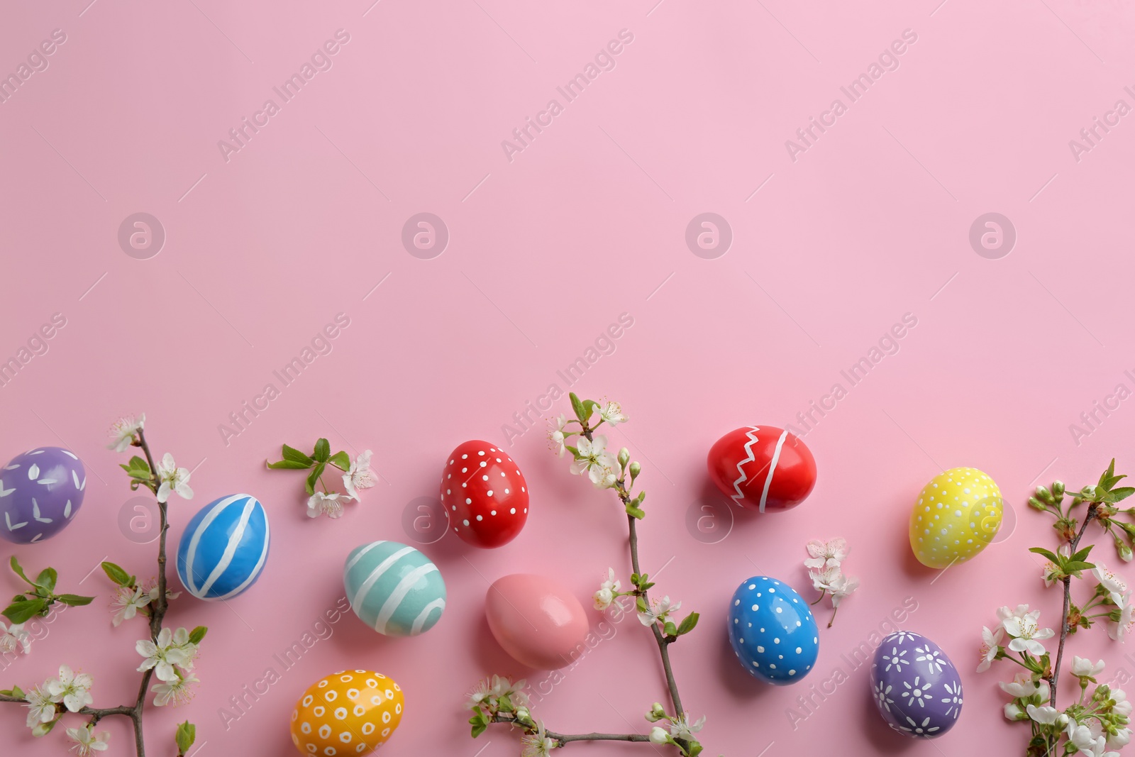 Photo of Flat lay composition with painted Easter eggs and blossoming branches on color background, space for text