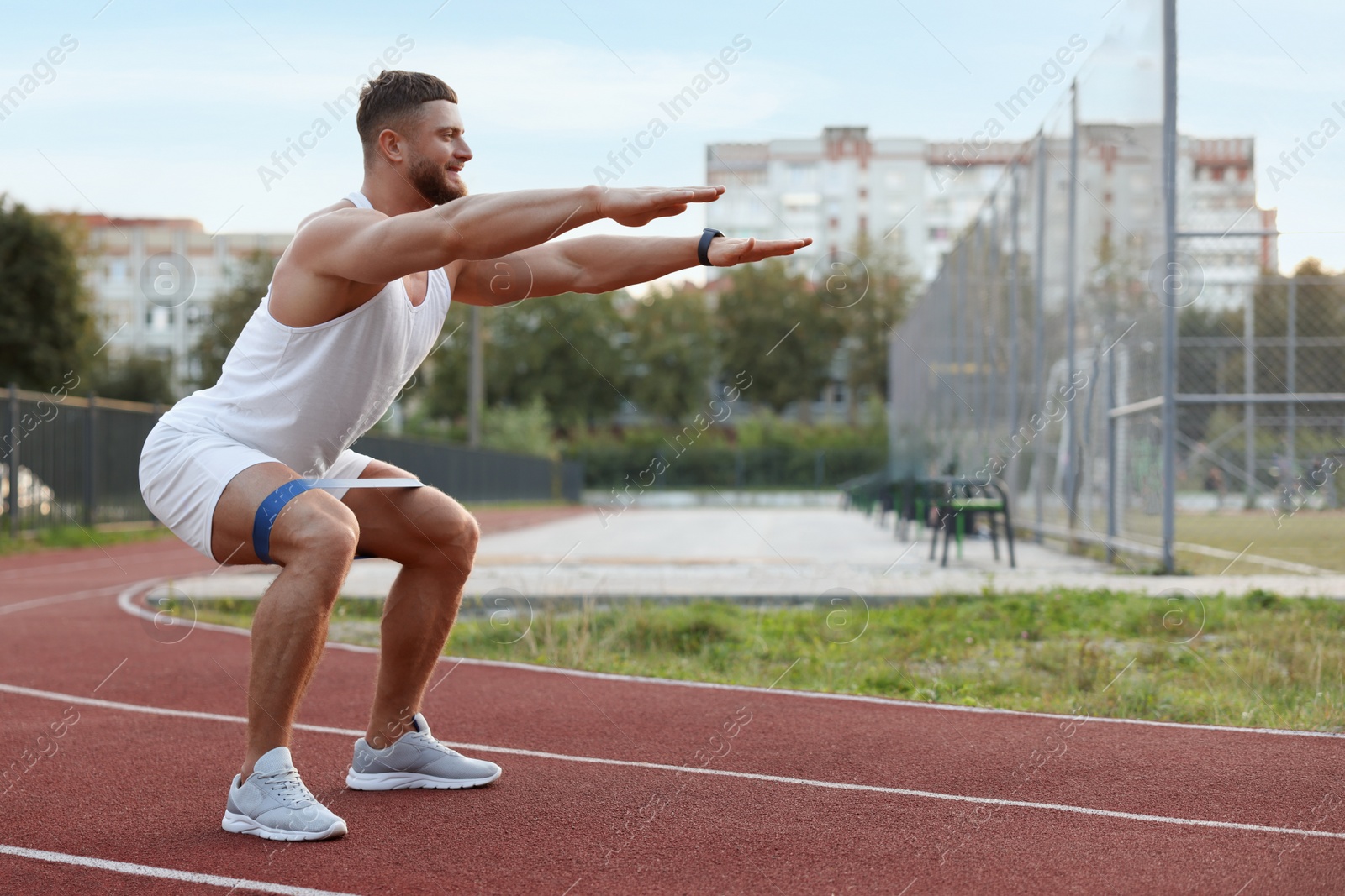 Photo of Muscular man doing exercise with elastic resistance band at stadium