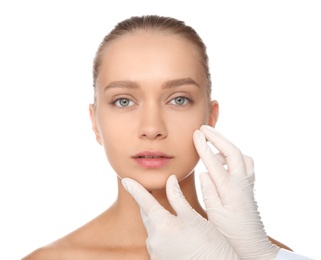 Doctor examining young woman face before cosmetic surgery on white background