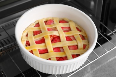 Photo of Baking dish with raw apple pie in oven, closeup