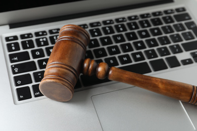 Photo of Wooden gavel on modern laptop, closeup. Cyber crime