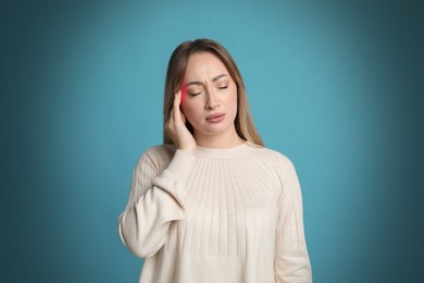 Young woman having headache on light blue background 