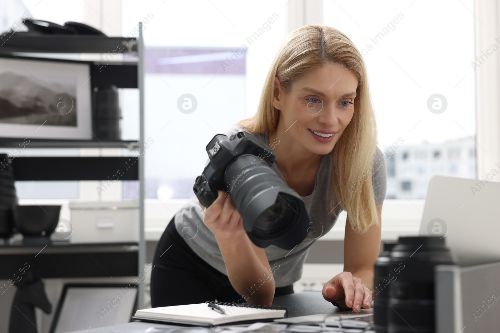 Photo of Professional photographer with digital camera at table in office