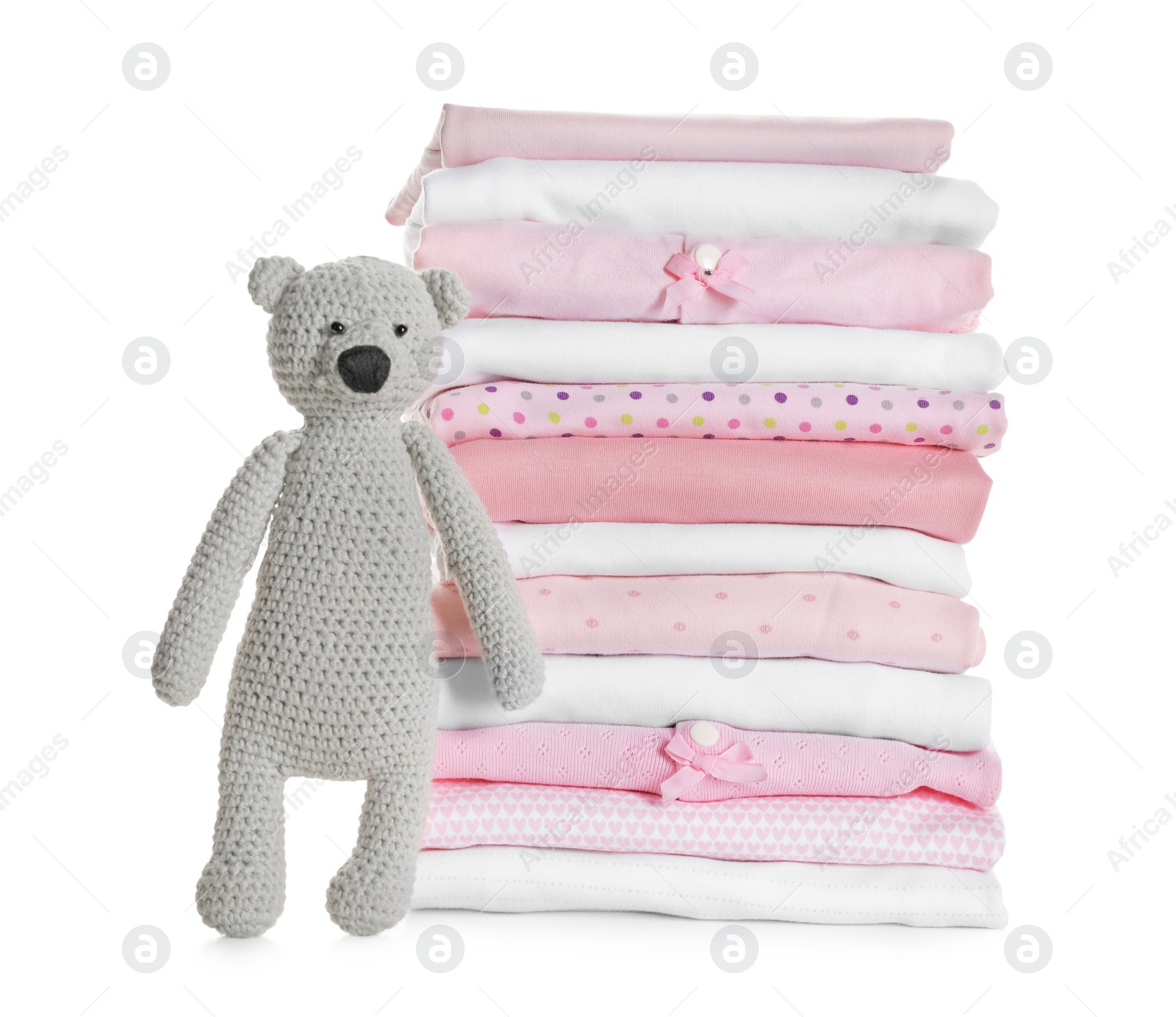 Photo of Stack of clean girl's clothes and toy bear on white background