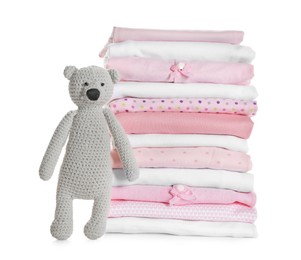 Stack of clean girl's clothes and toy bear on white background