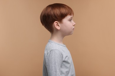 Hearing problem. Little boy on pale brown background