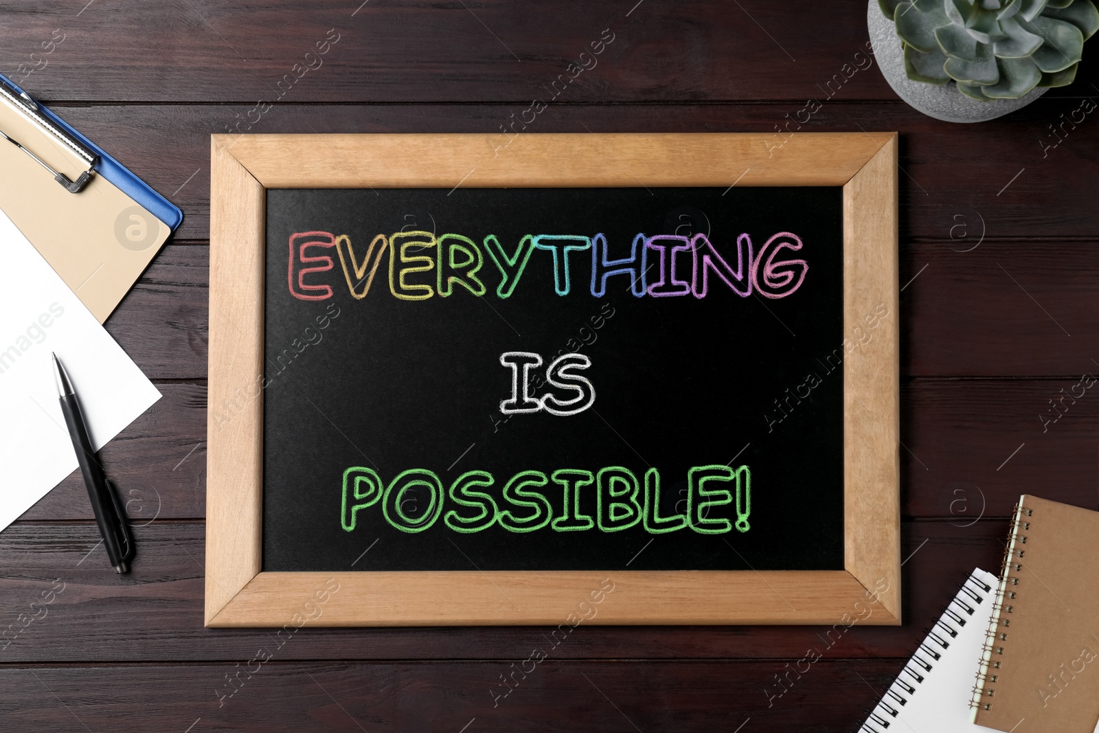 Image of Small chalkboard with motivational quote Everything is possible, plant and stationery on wooden table, flat lay