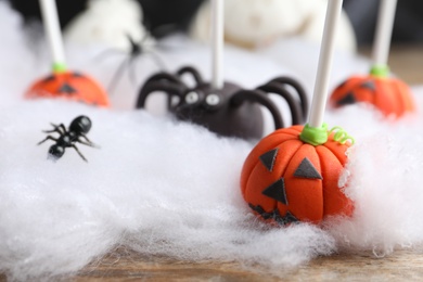 Photo of Different Halloween themed cake pops on wooden table, closeup