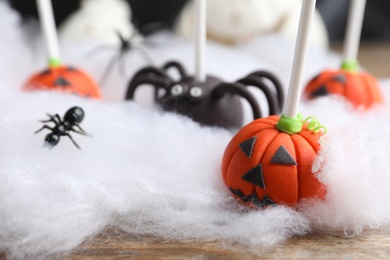 Different Halloween themed cake pops on wooden table, closeup