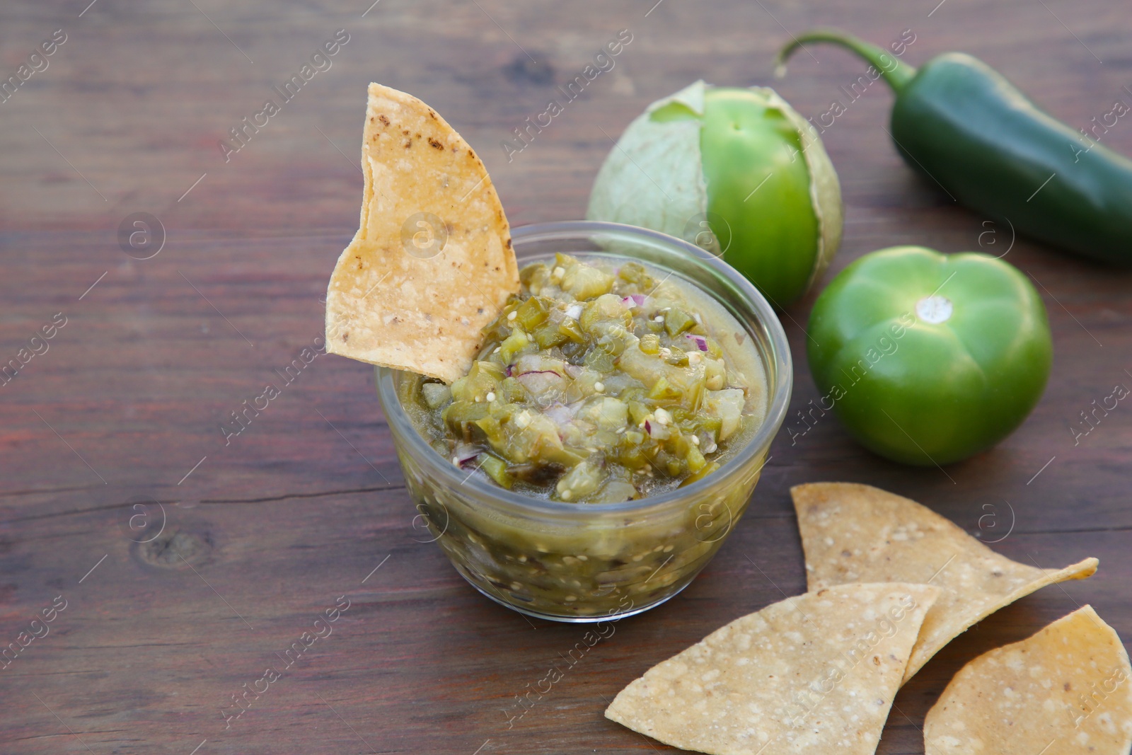 Photo of Tasty salsa sauce, ingredients and tortilla chips on wooden table, closeup