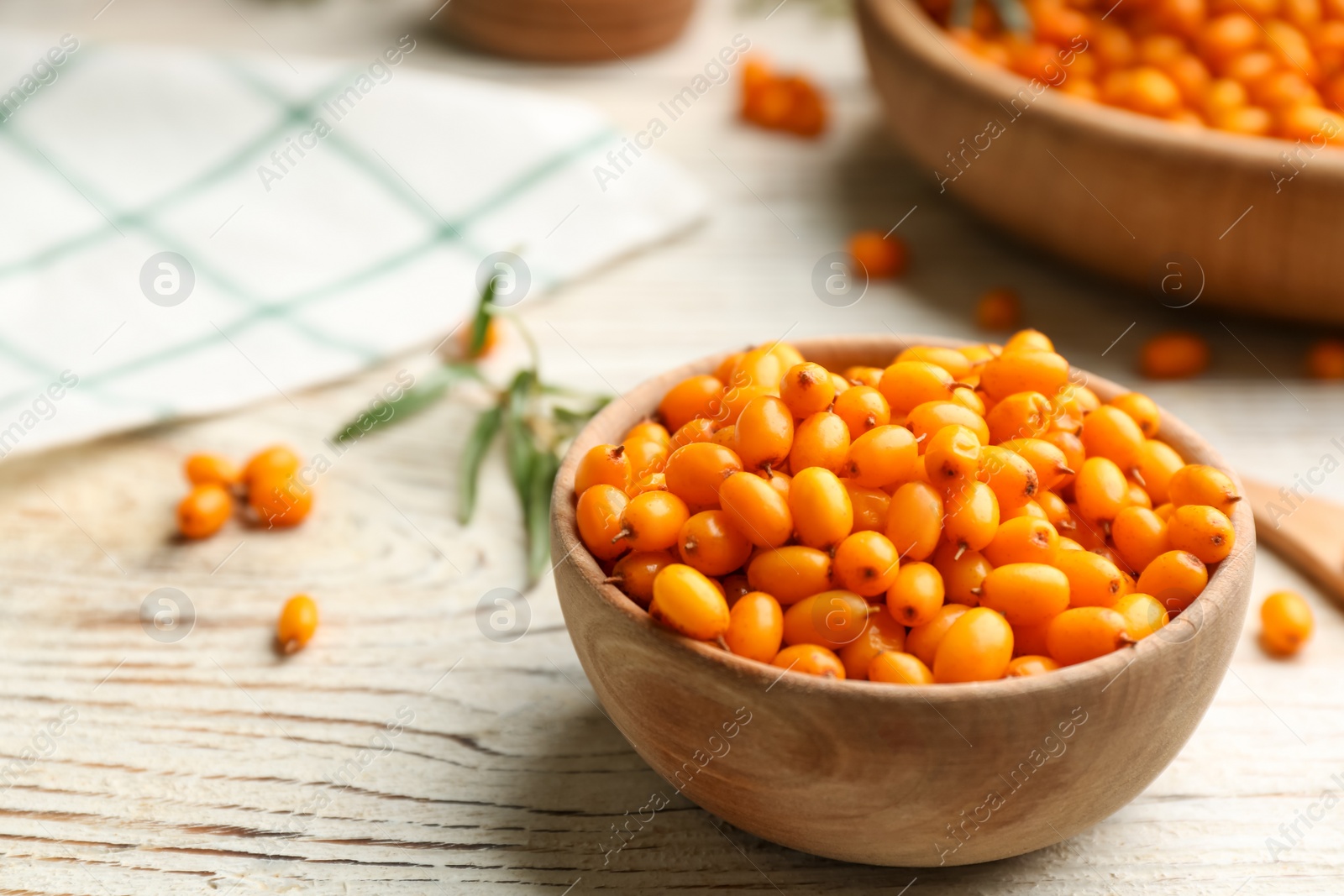 Photo of Fresh ripe sea buckthorn in bowl on white wooden table. Space for text