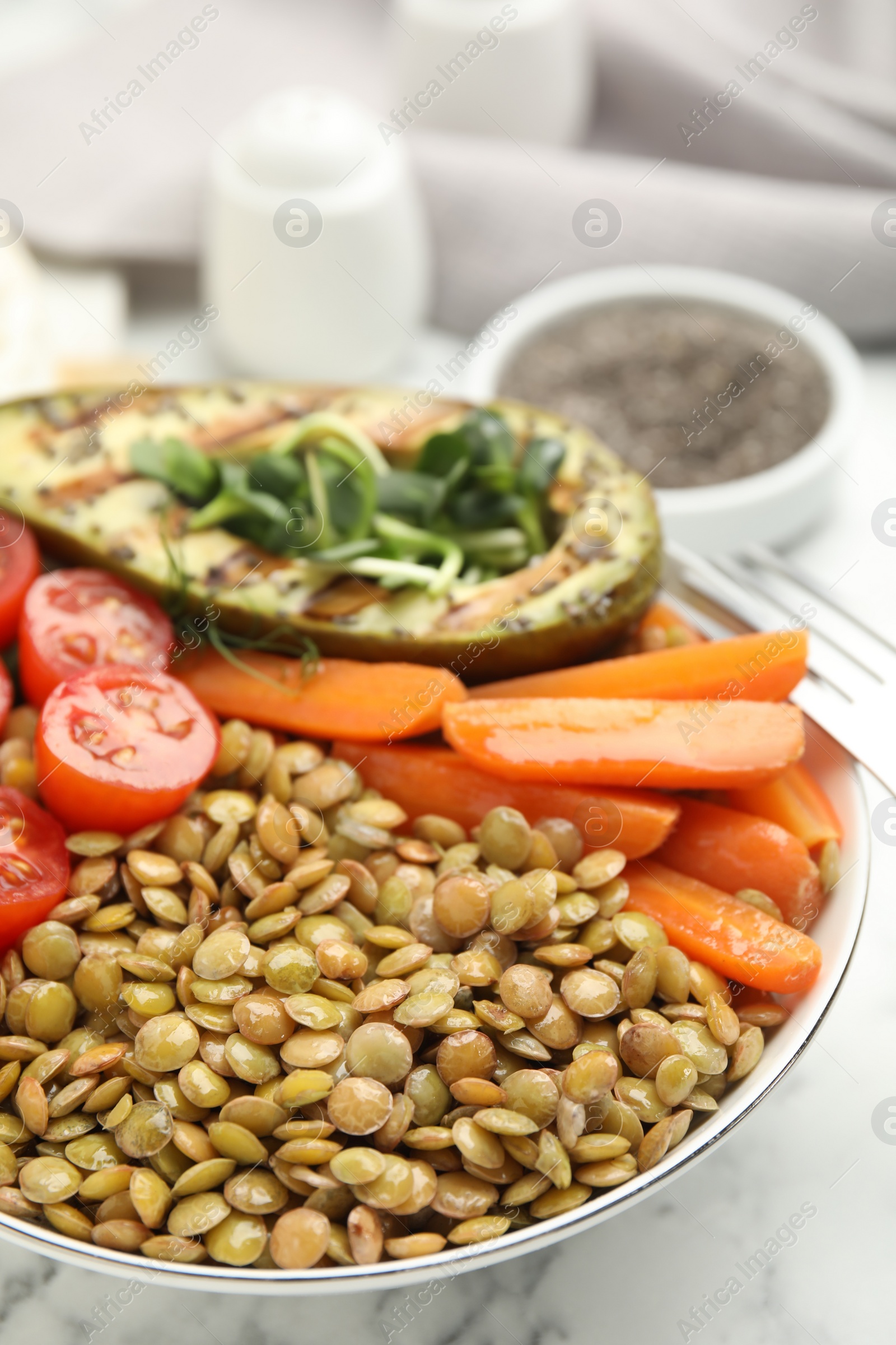 Photo of Delicious lentil bowl with avocado, tomatoes and carrots on white marble table