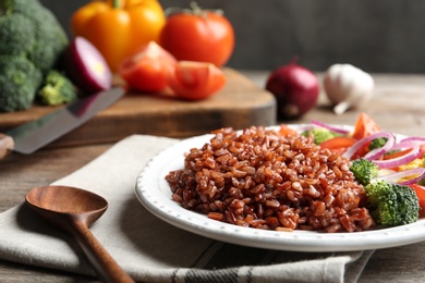 Photo of Plate of boiled brown rice with vegetables served on table, closeup. Space for text