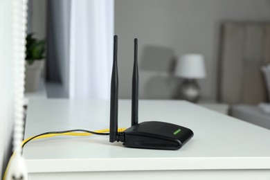 Photo of Modern Wi-Fi router on white table in room