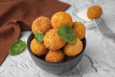 Photo of Bowl of delicious fried tofu balls with basil on textured table