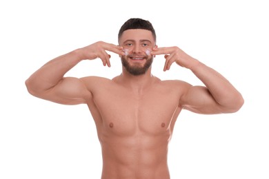 Handsome man applying cream onto his face on white background