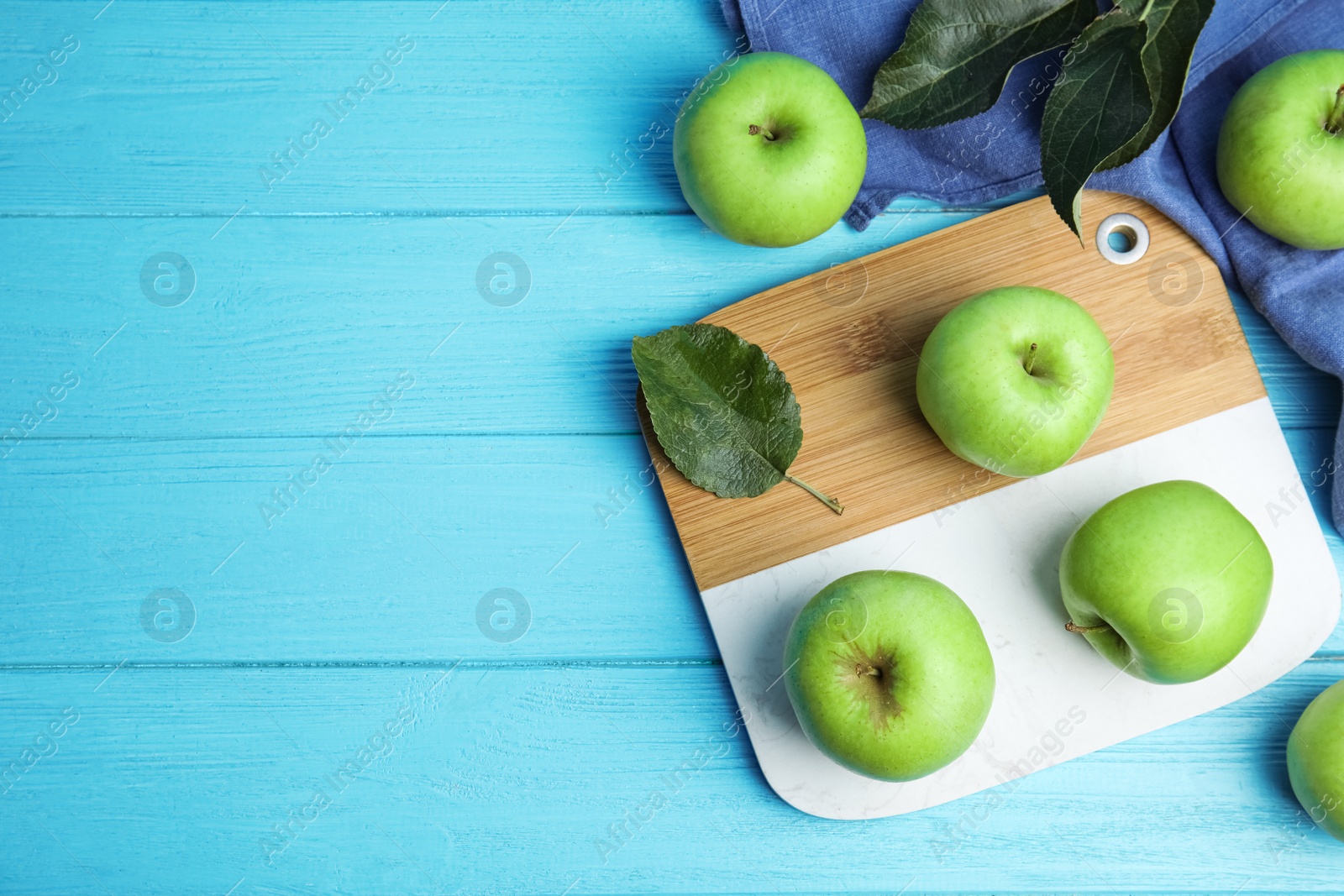 Photo of Ripe green apples on light blue wooden table, flat lay. Space for text