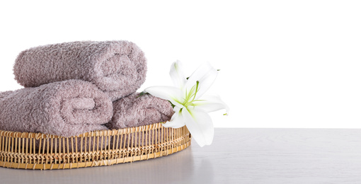 Photo of Fresh towels and lily flower on wooden table against white background. Space for text