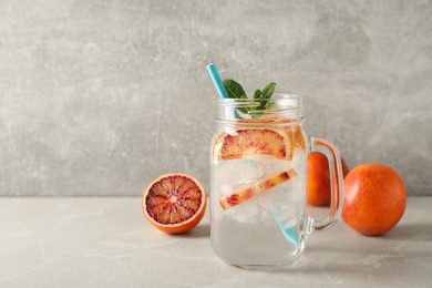 Photo of Delicious refreshing drink with sicilian orange and mint on grey table. Space for text