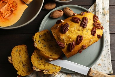 Delicious pumpkin bread with pecan nuts on wooden table, flat lay