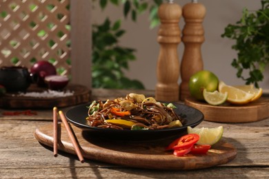 Photo of Stir-fry. Tasty noodles with meat and vegetables served on wooden table