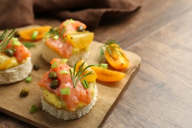 Photo of Tasty canapes with salmon served on wooden table, closeup. Space for text