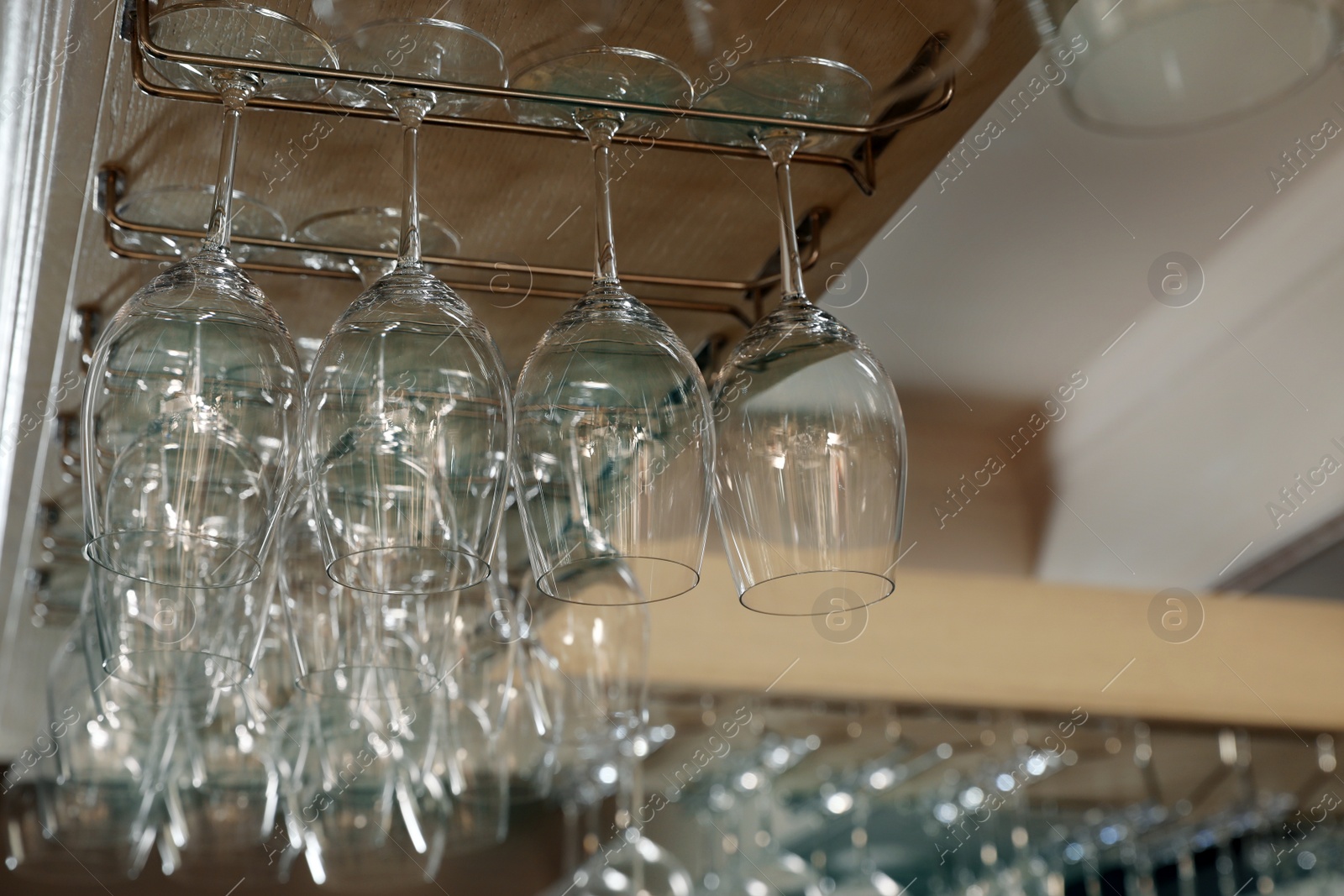 Photo of Set of empty clean glasses on bar racks