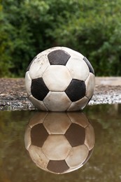 Photo of Dirty soccer ball in muddy puddle outdoors