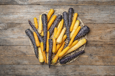 Photo of Many different raw carrots on wooden table, top view