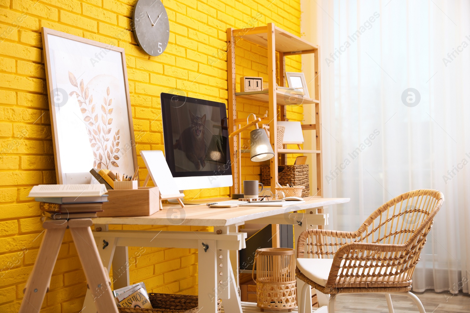 Photo of Stylish home office interior with comfortable workplace near yellow brick wall