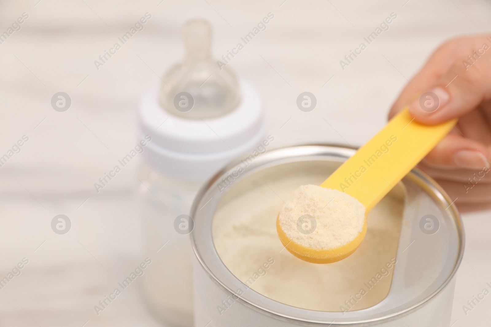 Photo of Woman with powdered infant formula at table, closeup and space for text. Preparing baby milk