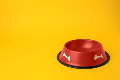 Photo of Empty red feeding bowl on orange background. Space for text