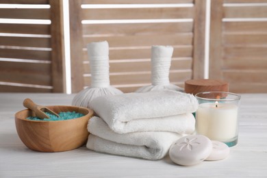 Spa composition with skin care products and burning candle on white wooden table