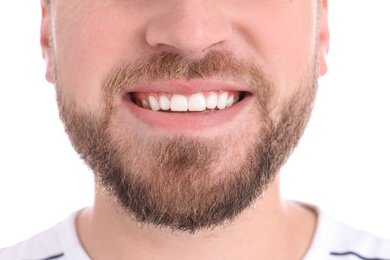 Young man with healthy teeth smiling on white background, closeup