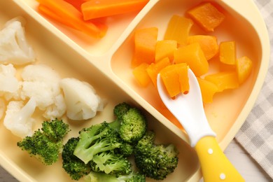Baby food. Section plate with different vegetables on wooden table, top view