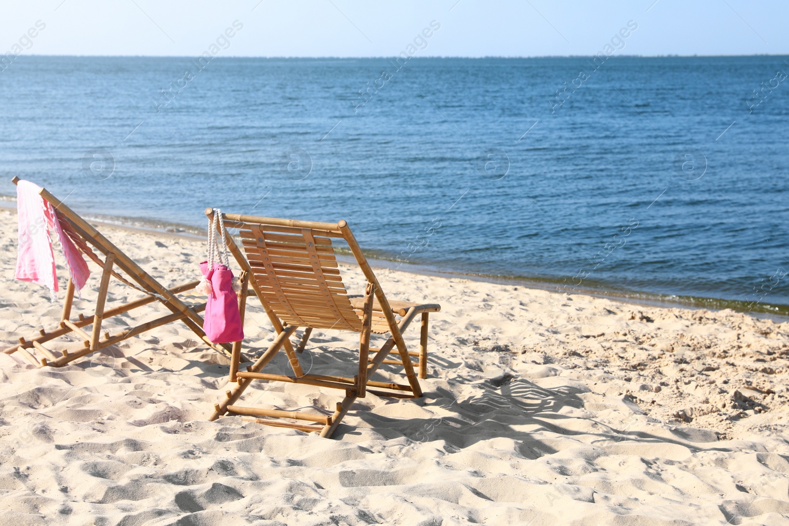 Photo of Empty wooden sunbeds and beach accessories on sandy shore