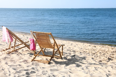 Empty wooden sunbeds and beach accessories on sandy shore