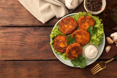 Tasty vegan cutlets with sauce and ingredients on wooden table, flat lay. Space for text