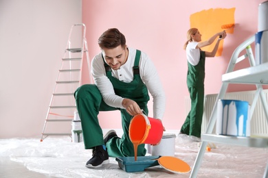 Professional decorator with bucket of paint indoors. Home repair service