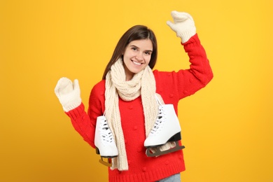 Photo of Happy woman with ice skates on yellow background